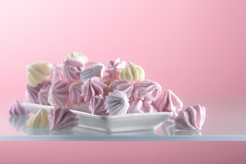 Homemade colorful meringue on a pink background.