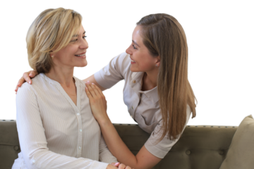 Beautiful middle aged mom and her adult daughter are hugging and smiling while sitting on couch on a transparent background