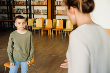 Teacher talking with school boy in library