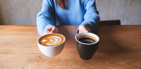 Closeup image of a woman holding and serving two cups of hot coffee