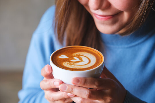 Closeup image of a woman holding a cup of latte coffee