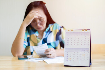 Front view owe Asian woman, female sitting on the chair at home, stressed and confused by calculate expense
