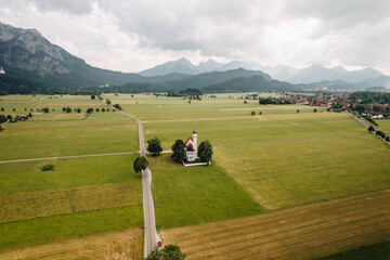 Aerial view of St Coloman church near Schwangau, cloudy day, Alps in background