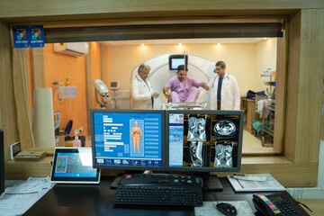 Doctors and patient in mri room at hospital. report showing on computer screen