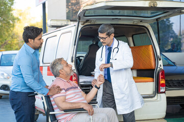 Doctor receiving old man from ambulance and checking while moaning in pain. © PRASANNAPIX