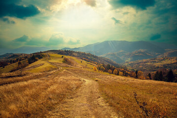 Mountain landscape on a sunny autumn day. View of the mountain slopes and dirt road. Beautiful...