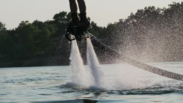 Man flying at the aquatic flyboard in slow motion. Large jet of water under high pressure propels a person above the water. Active people enjoy extreme water sports water sport. Lifestyle, Recreation