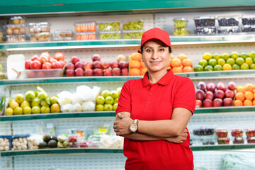 Young and confident female seller standing at supermarket.