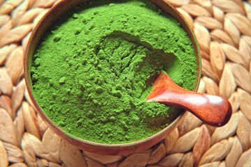 Wooden spoon with powdered matcha tea in a bowl spinning on natural background. Matcha powder. Top view, Closeup. Finely ground green powder. Japanese culture. Healthy eating with high antioxidants.