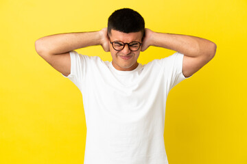 Young handsome man over isolated yellow background frustrated and covering ears