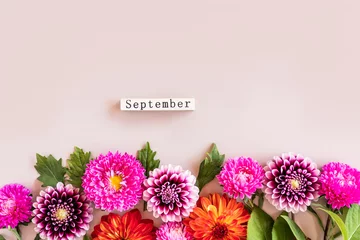 Schilderijen op glas Festive autumn background for the holiday. Border of bright dahlia heads and September text from a wooden calendar on a pastel background. © Marina