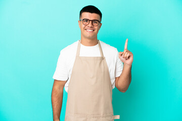 Restaurant waiter man over isolated blue background pointing with the index finger a great idea