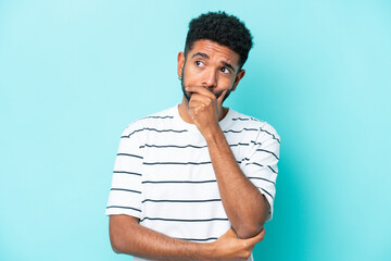 Young Brazilian man isolated on blue background having doubts and with confuse face expression