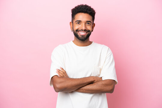 Young Brazilian man isolated on pink background keeping the arms crossed in frontal position