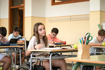 A differently abled preteen in a wheelchair in a high school classroom. Back to school concept with integration