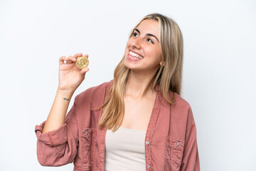 Young caucasian woman holding a Bitcoin isolated on white background looking up while smiling