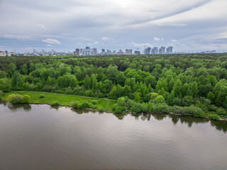 Big lake with green shores in bright sun light and city on horizon, aerial landscape. Recreation concept. Aerial view
