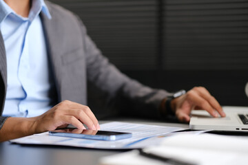 Millennial businessman wearing formal wear working with statistical document in modern office