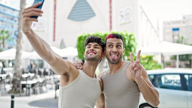 Two men couple smiling confident make selfie by smartphone at coffee shop terrace