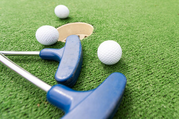 Fun vacation entertainment for summertime. Playing mini golf on green grass outdoors. Setting goals and winning lifestyle concept. Competition at golf course: two crossed sticks. Blank space for copy.