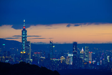 Fototapeta premium At dusk, the night view of Taipei gradually brightens. Dynamic clouds. View of the urban landscape from Dajianshan Mountain, New Taipei City.