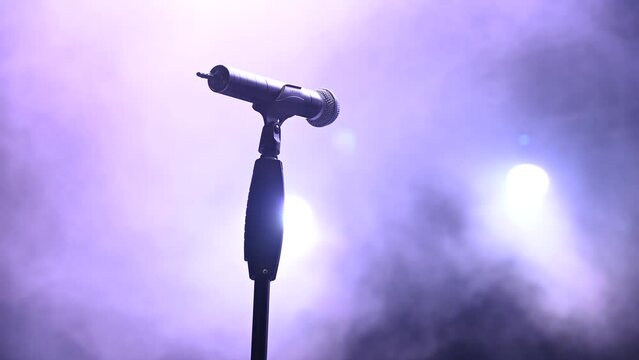 Microphone on the stage. Vocal mic with fog and lights in background. Concert. 