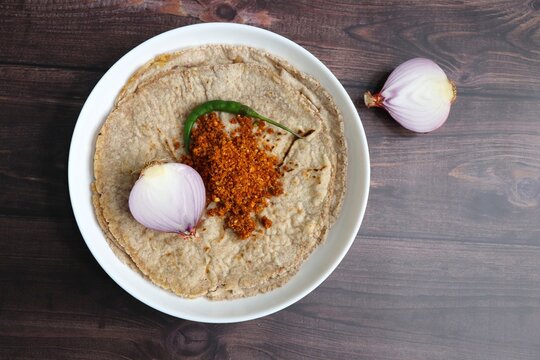 Jowar flour flatbread known as bhakar or jawari bhakri. served with spicy garlic or lasun chutney, green chilli and onion. farmer's food. Maharashtrian village food. copy space
