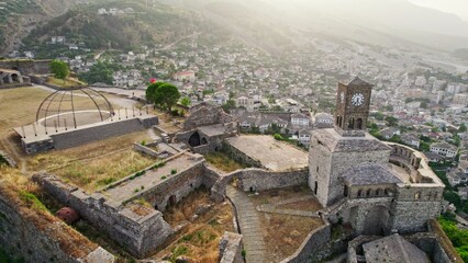Flying around Gjirokaster Fortress Castle during sunset in Albania. Old stone houses, valley and mountains in the background. Gjirokastra one of the most beautiful cities in Albania