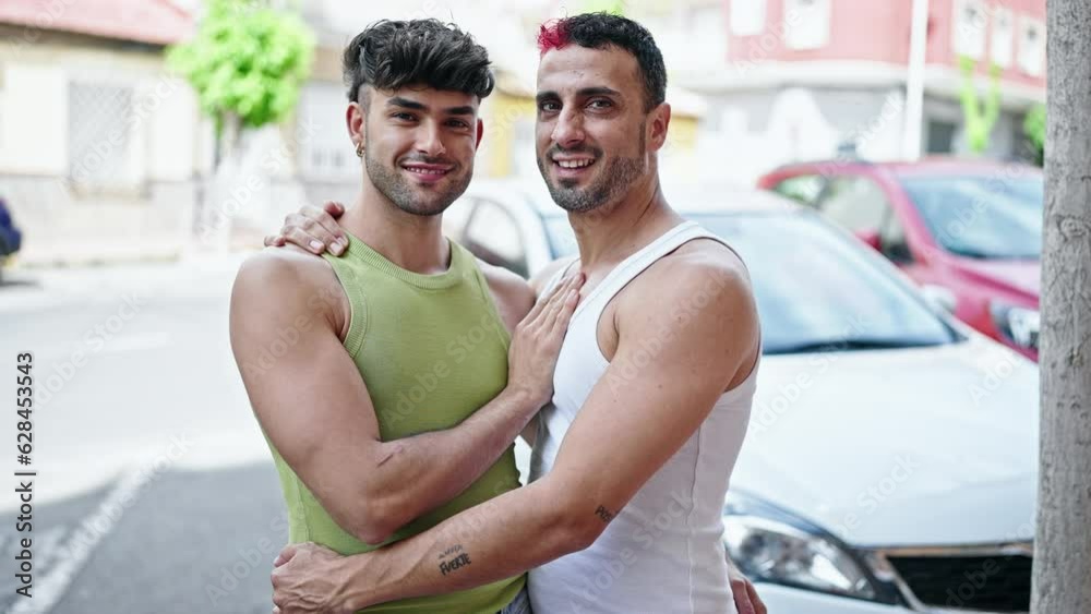 Wall mural two men couple smiling confident hugging each other at street