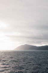 A moody image of a coastline taken off the deck of a ship. If you look closesly you'll see widmills on the hills
