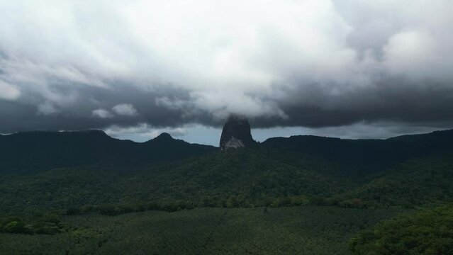 Aerial view of stormy clouds moving over the Pico Cao Grande peak, in Sao Tome, Africa