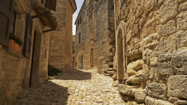 Camera moves along stones street of old town of Lacoste. Walk through picturesque village of Lacoste, Petit Luberon, Provence, France. Gimbal 4K shot