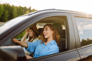 Fototapeta na wymiar Portrait of two young women on a car trip having fun, smiling, chatting together, enjoying nature. Active lifestyle, travel, tourism, nature.