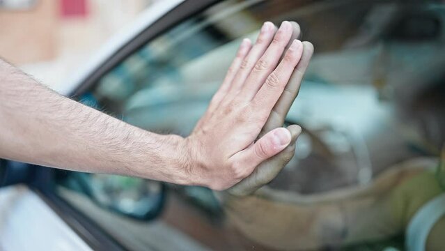 Two men with hands together on car window saying goodbye at park