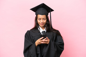 Young university Colombian woman graduate isolated on pink background sending a message with the mobile