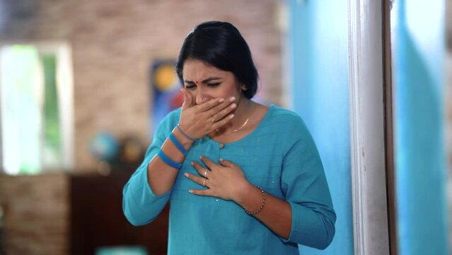 An young indian woman is unwell, coughing and sneezing as she battles with illness. She seeks rest and recovery, hoping to regain her health soon.