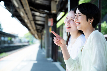 Two young, beautiful Asian women happily chatted at the train. Tourism and lifestyles
