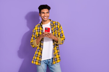 Photo of funky dreamy guy dressed checkered yellow shirt texting apple iphone samsung device empty space isolated purple color background