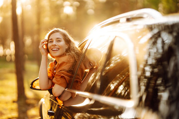 Feeling of freedom on beautiful sunny summer road. Shot of an attractive woman leaning out of car window while driving. Active lifestyle, travel.