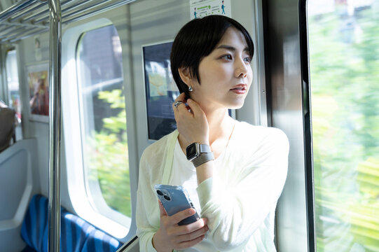 A Young Asian Woman Riding A Train With A Smartphone.  Travelling On Public Transportation