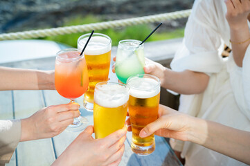 Young Asian girls toasting drinks at a seaside restaurant, smiling joyfully