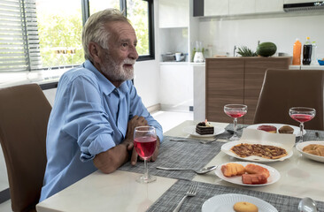 Eldery man sitting at dining table having dinner with family 