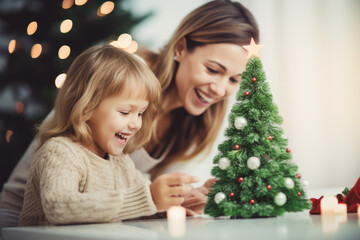Fototapeta na wymiar People, family, celebration and holidays concept. Mother and daughter making paper Christmas tree decoration at home.
