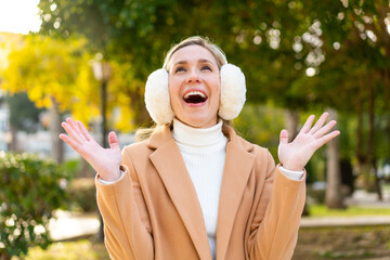 Young blonde woman wearing winter muffs at outdoors smiling a lot