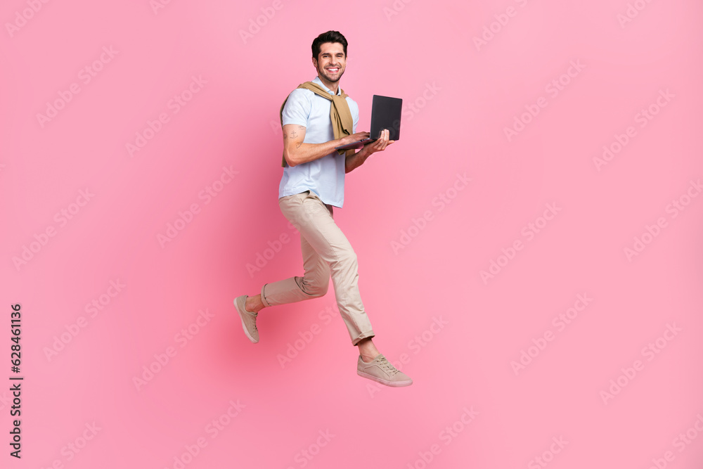 Poster Full length profile photo of excited person jumping run hold netbook empty space isolated on pink color background
