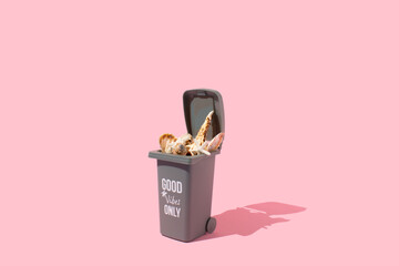 Trash can full of seshells on a pastel pink background. Minimal summer marine life nature concept. Sustainable environment idea.