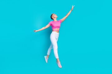 Fototapeta premium Full size photo of attractive young woman raise hand flying jump dressed stylish pink clothes isolated on cyan color background