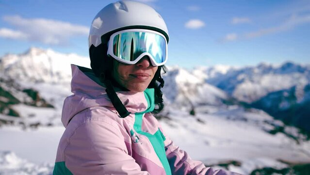 Close-up portrait of woman snowboarder skyer in ski helmet and glasses in mountains, side view. Girl wearing in ski clothes in winter resort. Enjoy healthy sport active rest, snowboarding lifestyle.