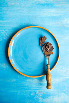 Pieces of different kinds of chocolate on spoon on blue plate