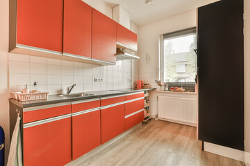 a kitchen area with red cabinets and white tiles on the walls, along with an open door that leads to a window